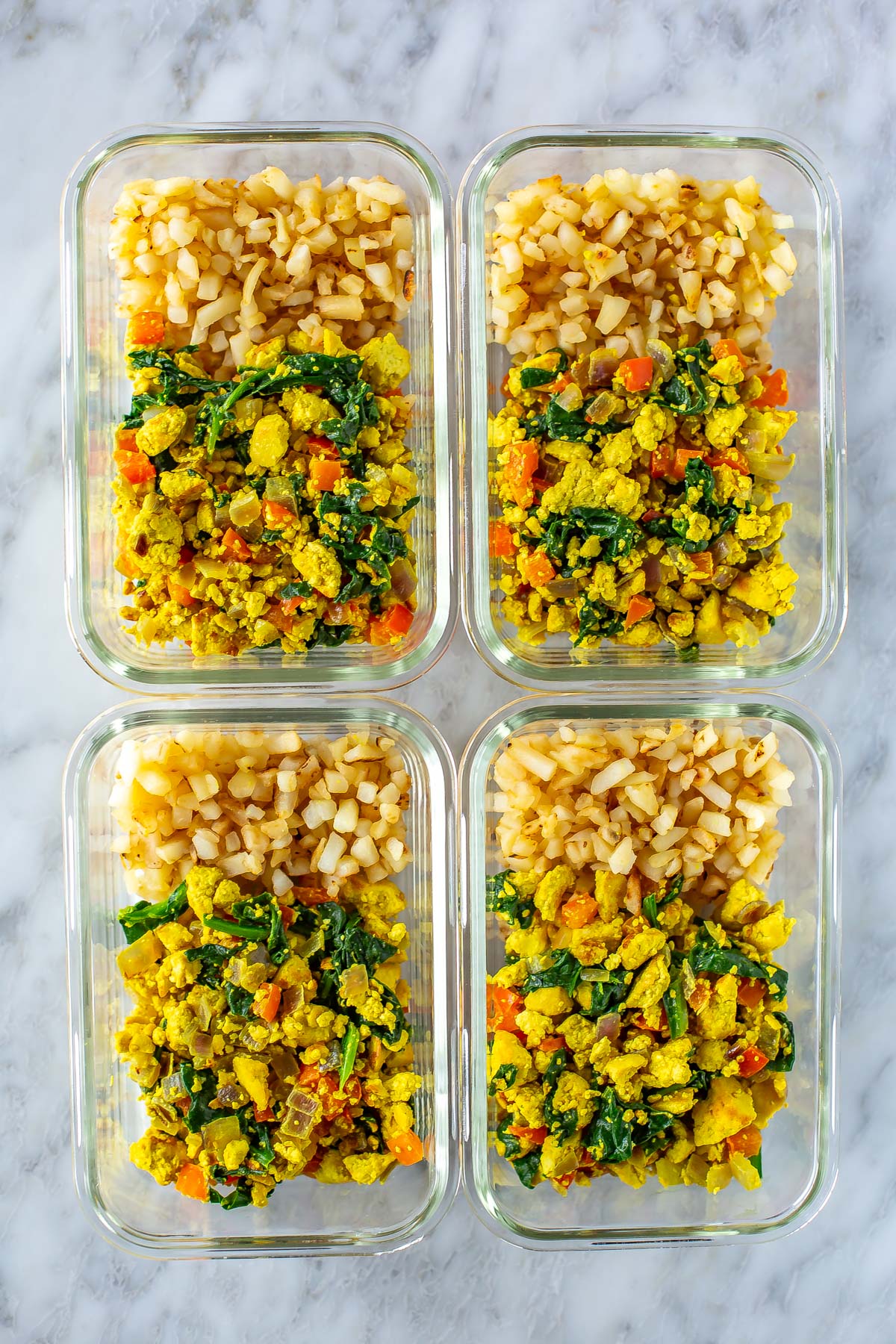 4 meal prep containers, each with a serving of tofu scramble and hashbrowns. 
