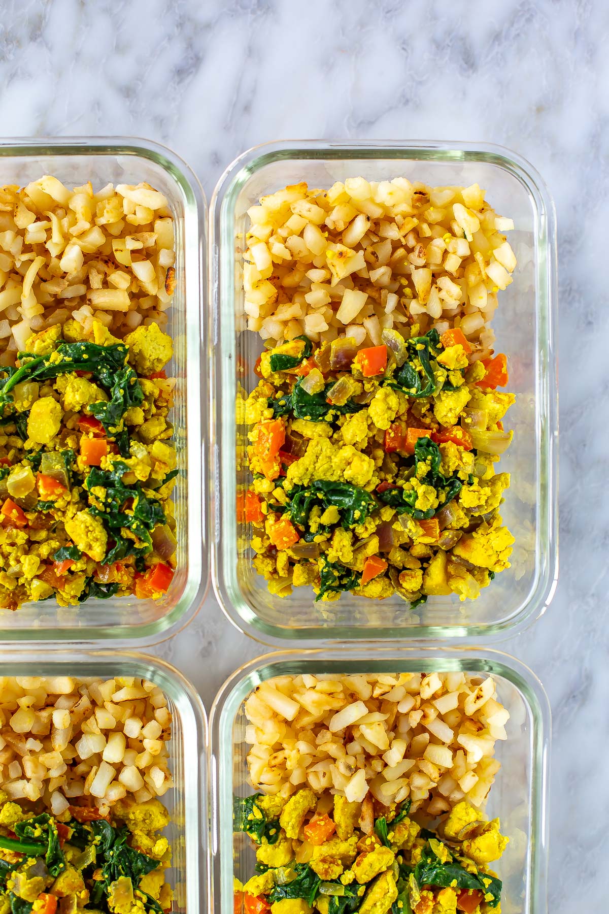 A close-up of a meal prep bowl with tofu scramble and hashbowns.