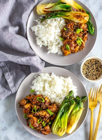 Two plates of ginger chicken served with bok choy and rice.