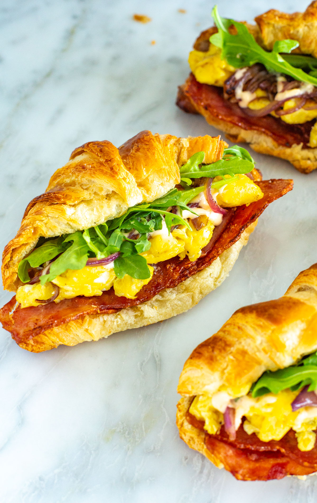 A close-up of a croissant breakfast sandwich.