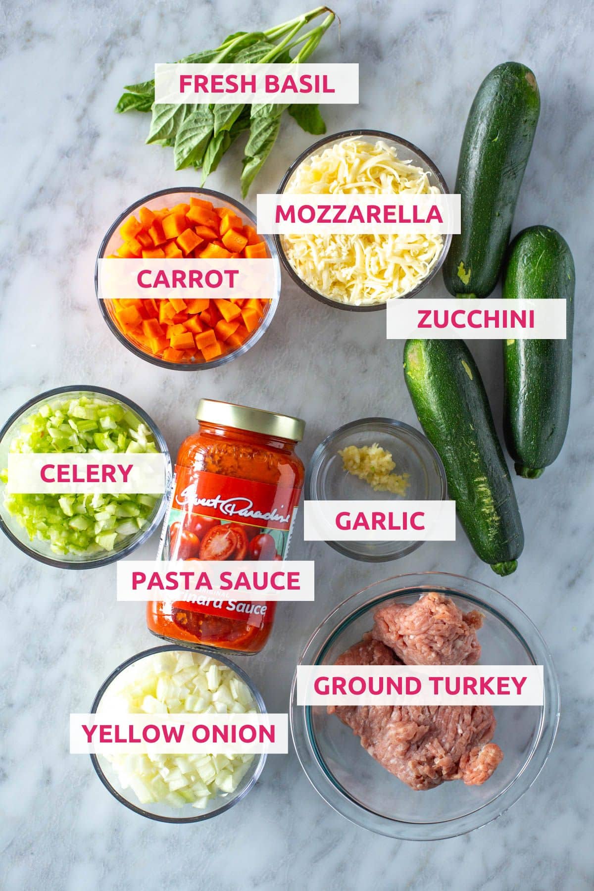 Ingredients for Italian stuffed zucchini boats: fresh basil, mozzarella, carrot, zucchini, celery, pasta sauce, garlic, yellow onion and ground turkey