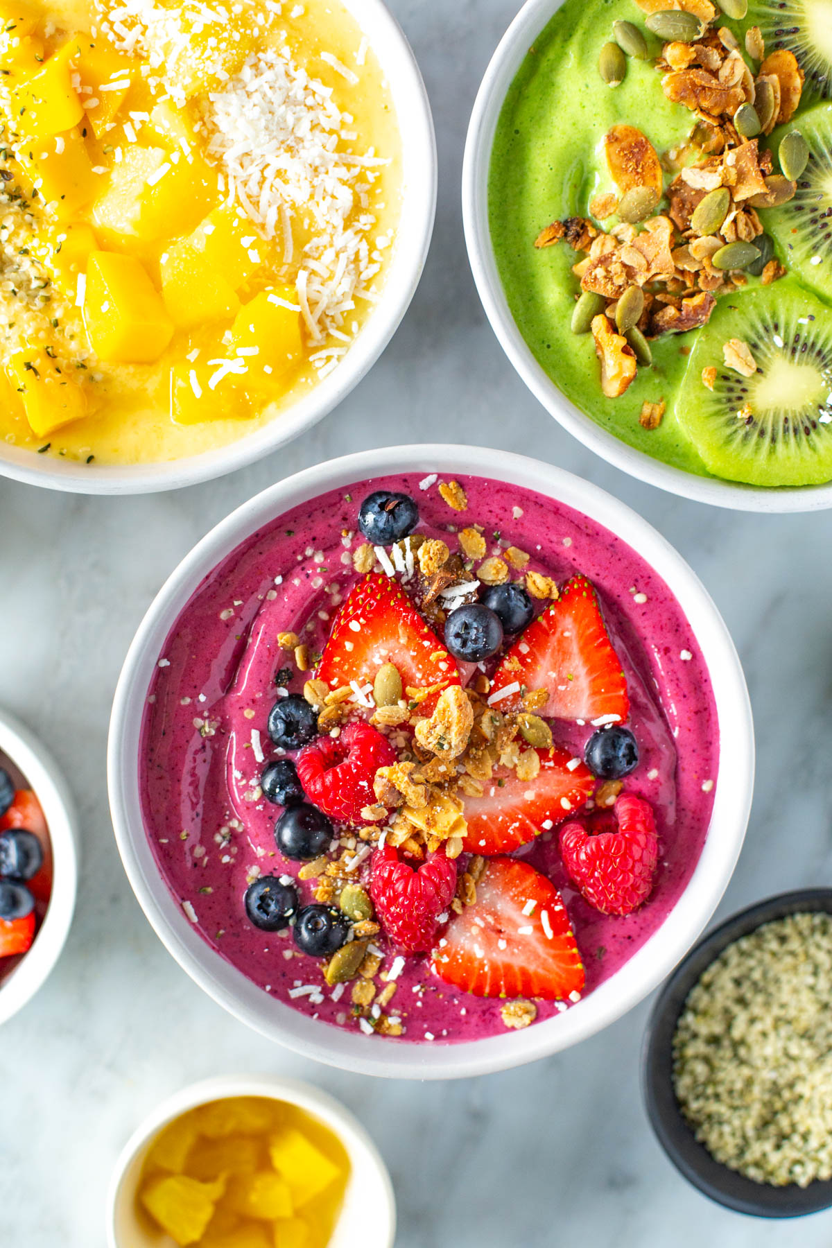 Three smoothie bowls with various toppings.