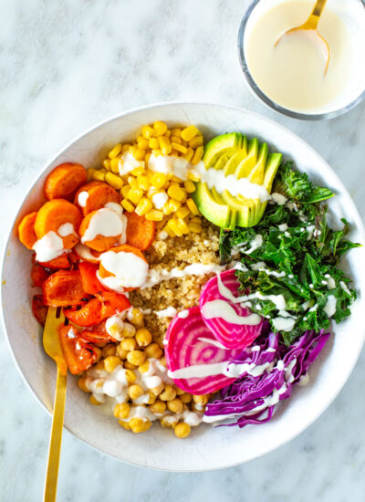 A rainbow veggie bowl with garlic dressing drizzled on top.