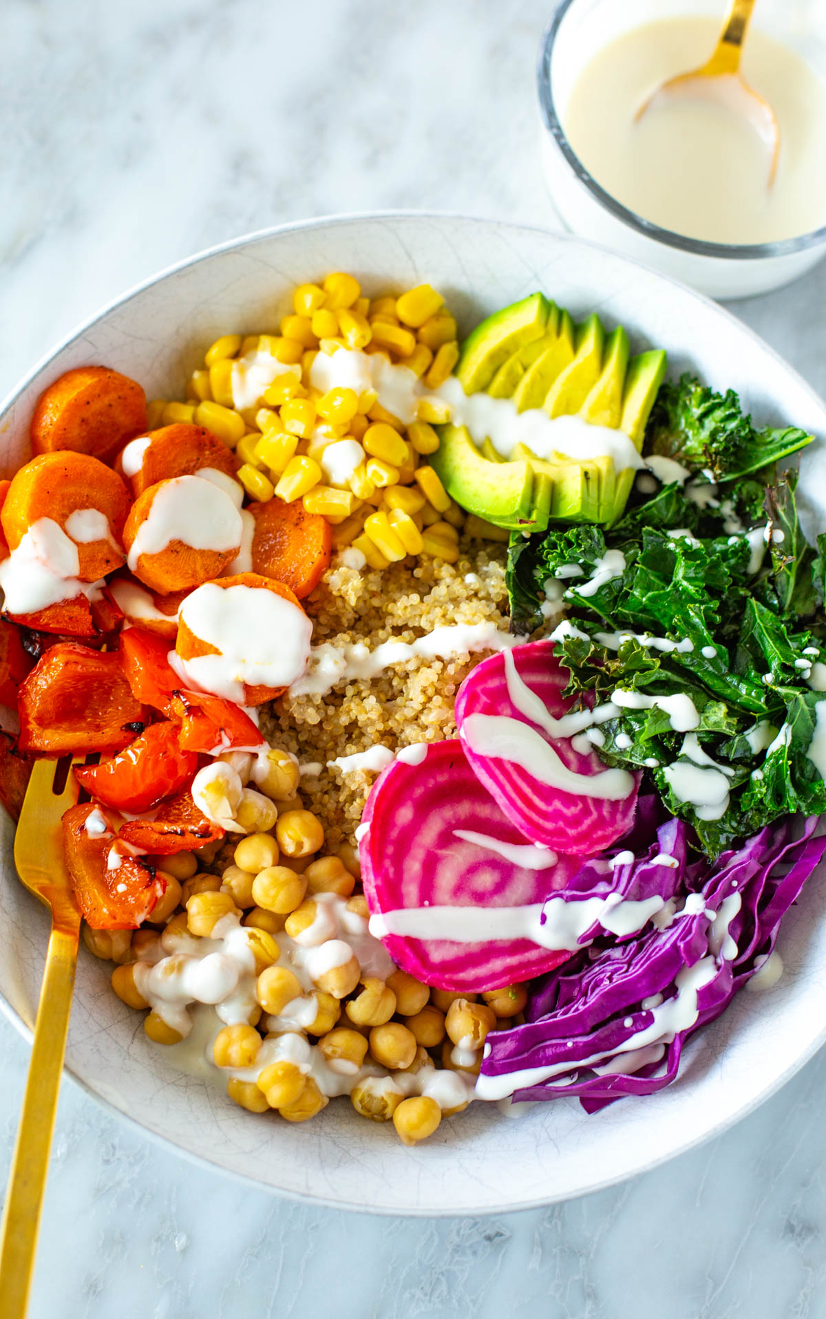 A rainbow veggie bowl with garlic dressing drizzled on top.
