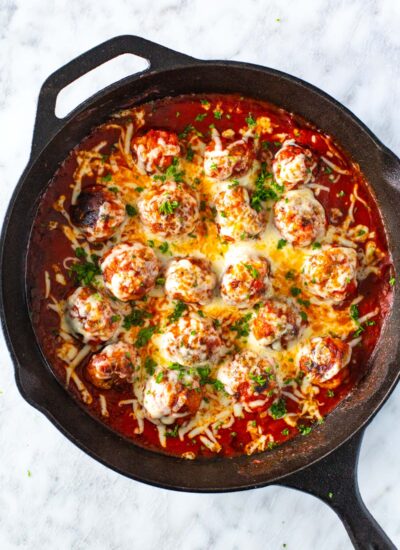 A skillet of chicken parm meatballs topped with mozzarella cheese.