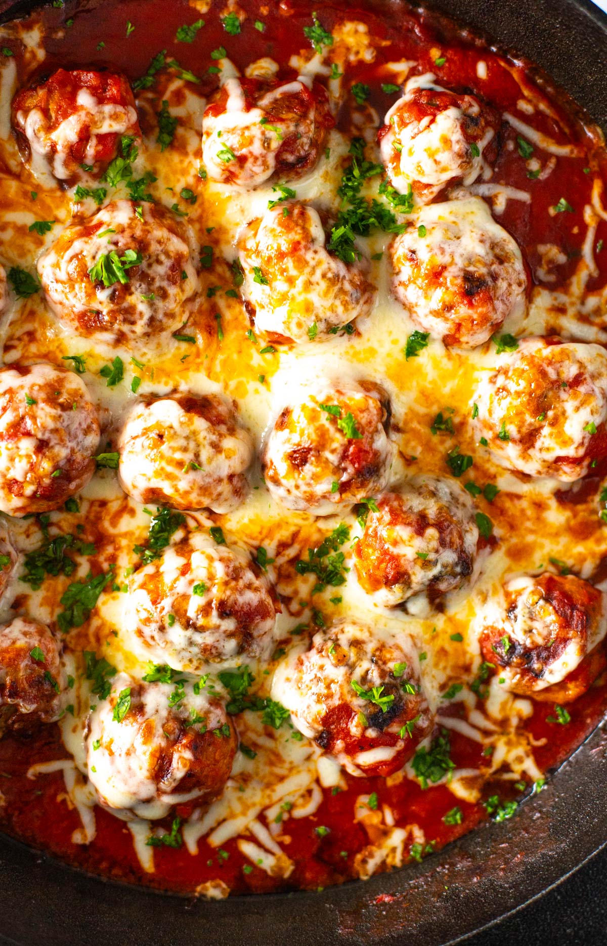 A close-up of chicken parm meatballs topped with melted mozzarella cheese.