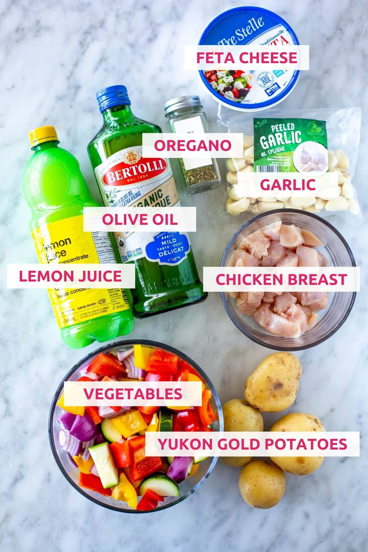 Ingredients for making sheet pan Greek chicken: feta cheese, olive oil, lemon juice, garlic, chicken breasts, vegetables, and Yukon gold potatoes