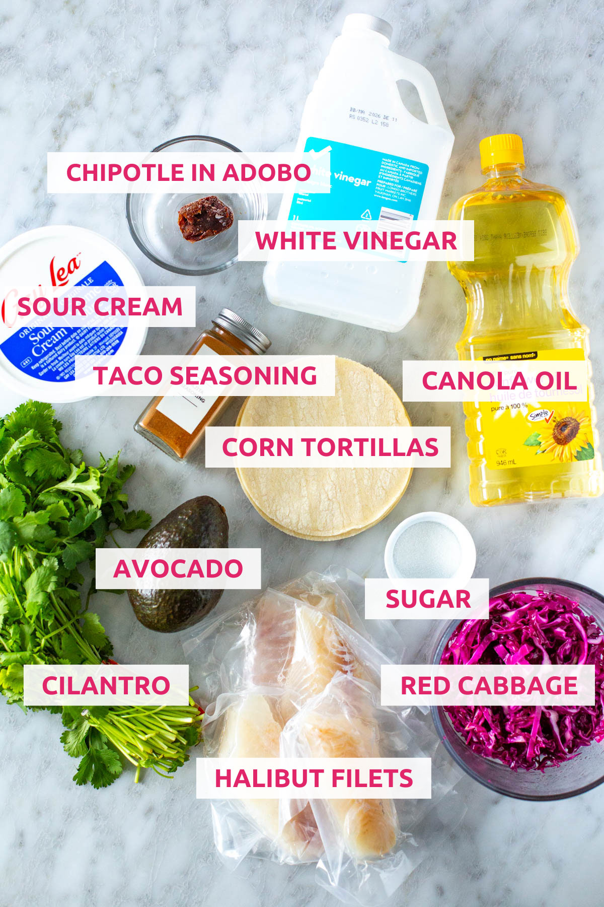 Ingredients for fish tacos: halibut filets, cilantro, avocado, red cabbage, sugar, canola oil, corn tortillas, taco seasoning, sour cream, chipotles in adobo and white vinegar.
