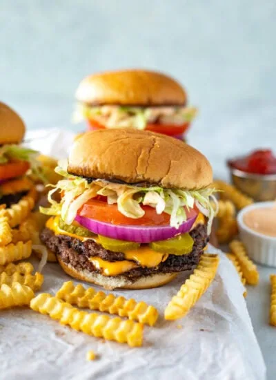 A homemade smash burger with some fries in front of it.