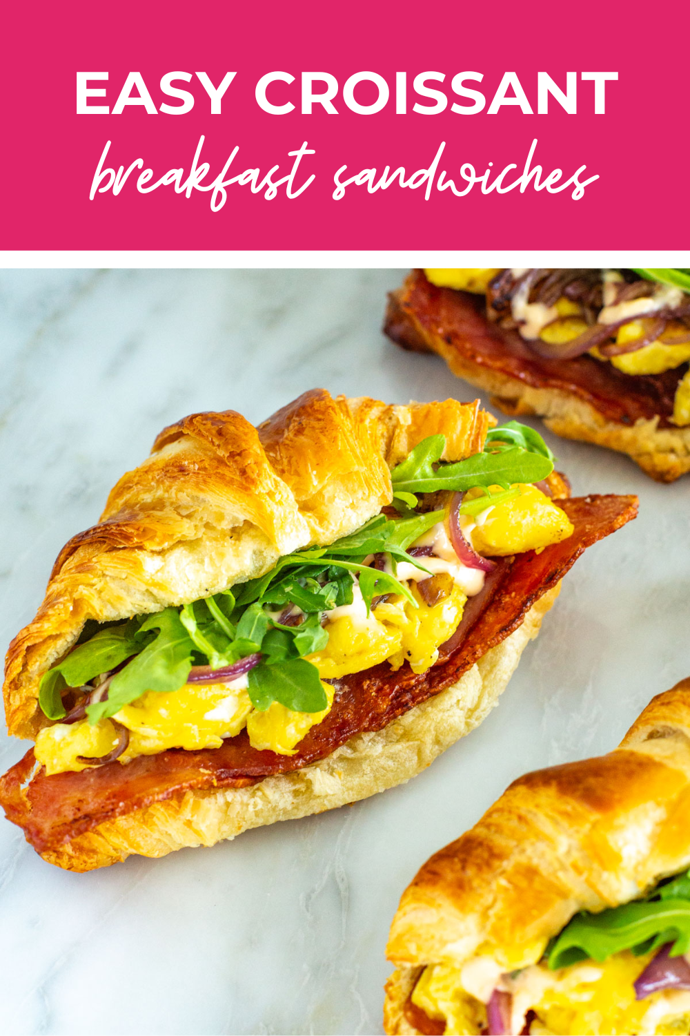 overhead shot of plated dish with pink banner on the top - reading "croissant breakfast sandwiches"