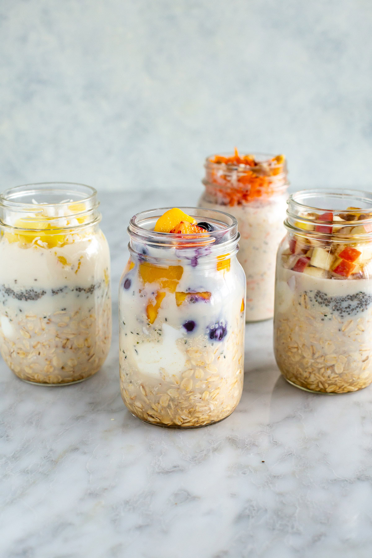 side front shot of four mason jars with overnight oats, each with different toppings
