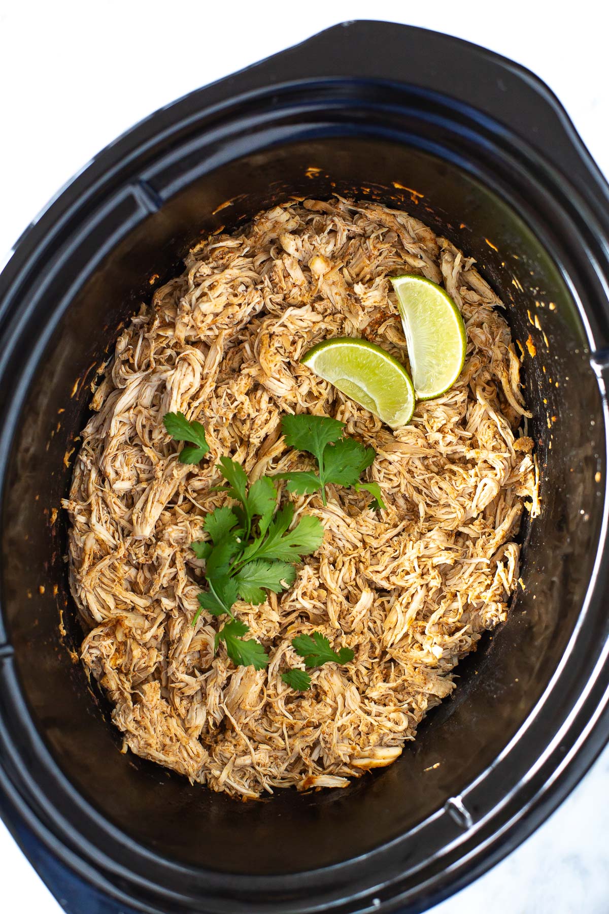 overhead shot of shredded chicken in a slow cooker - 1