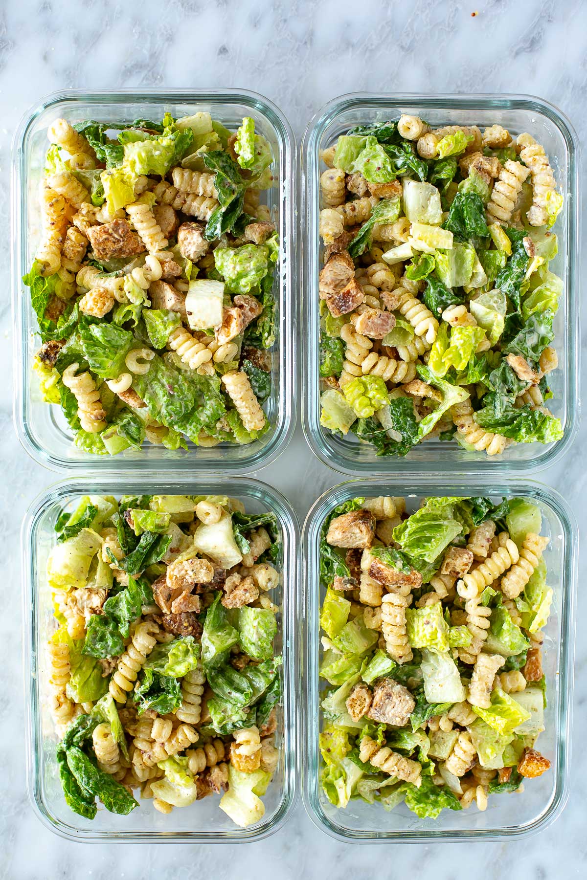 Overhead shot of meal-prep of chicken Caesar pasta salad