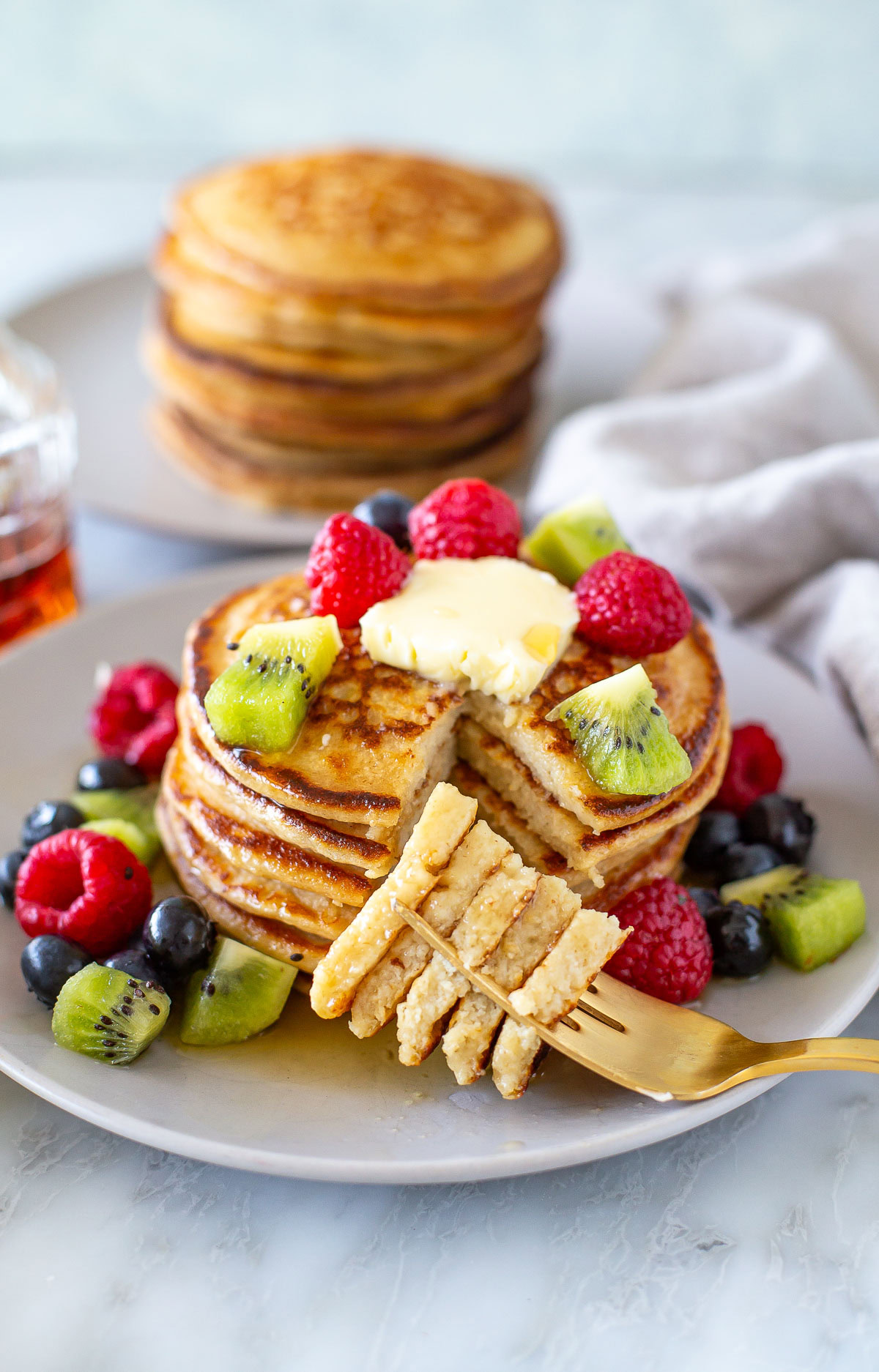 Overhead shot of cottage cheese pancakes with berries on top and around with sliced one
