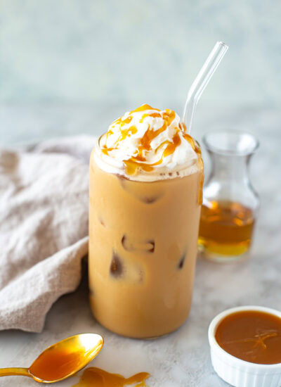 Side shot of an iced caramel latte with whipped cream and caramel drizzle.