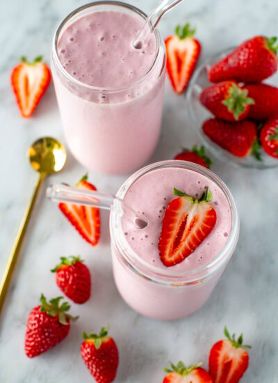 overhead shot of high protein strawberry smooth in 2 clear glasses and some strawberries around them 1