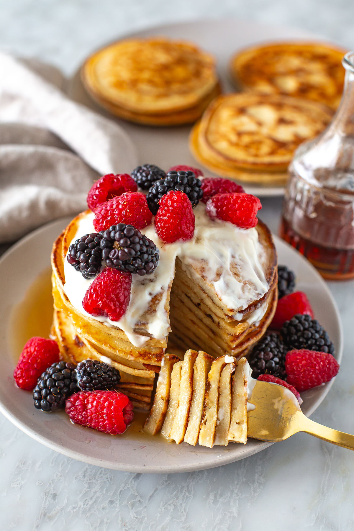 Side shot of a stack of Greek yogurt pancakes with berries and yogurt.