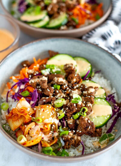 Side shot of a Korean Beef Bowl with another bowl blurred in the background.