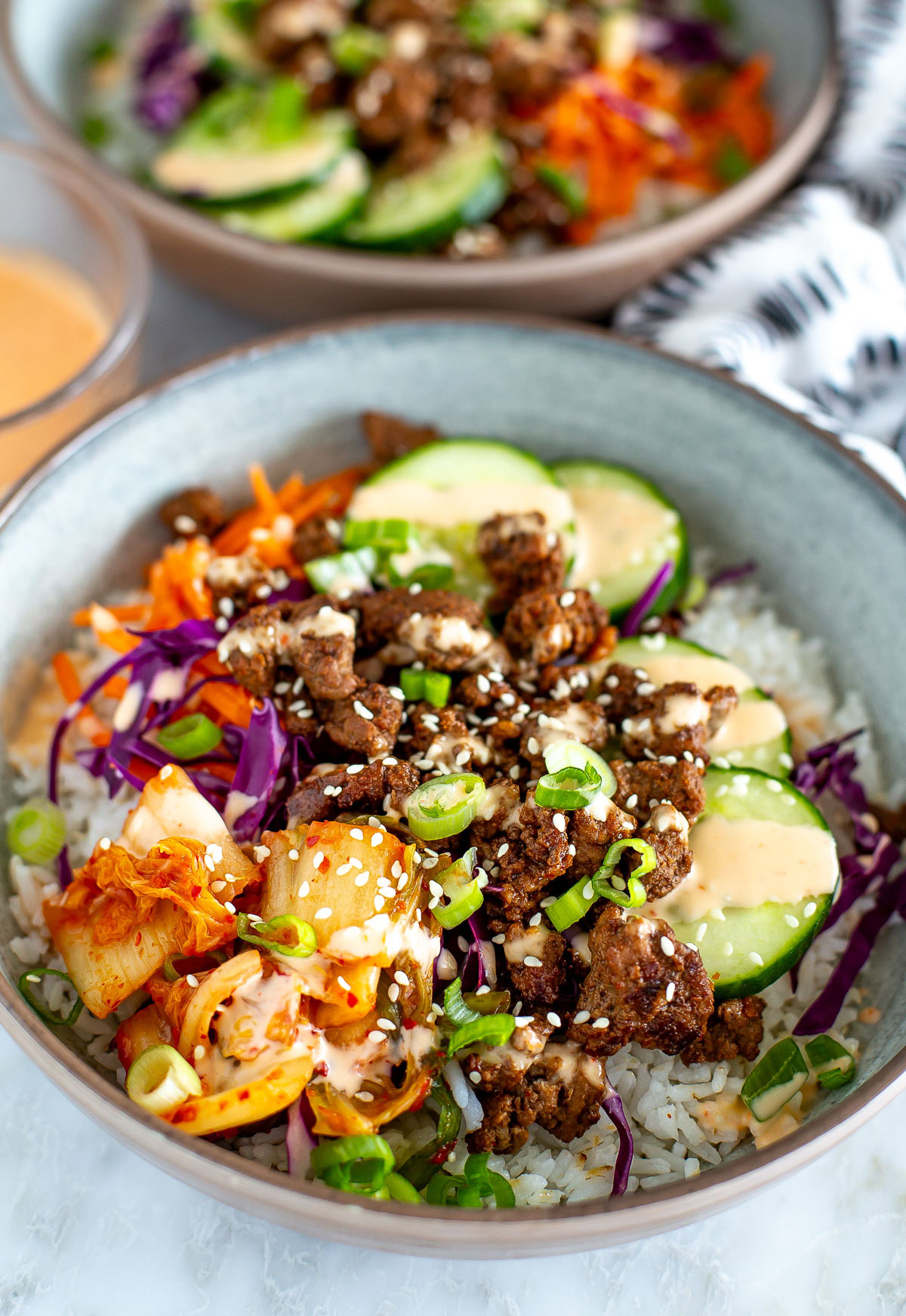 Side shot of a Korean Beef Bowl with another bowl blurred in the background.