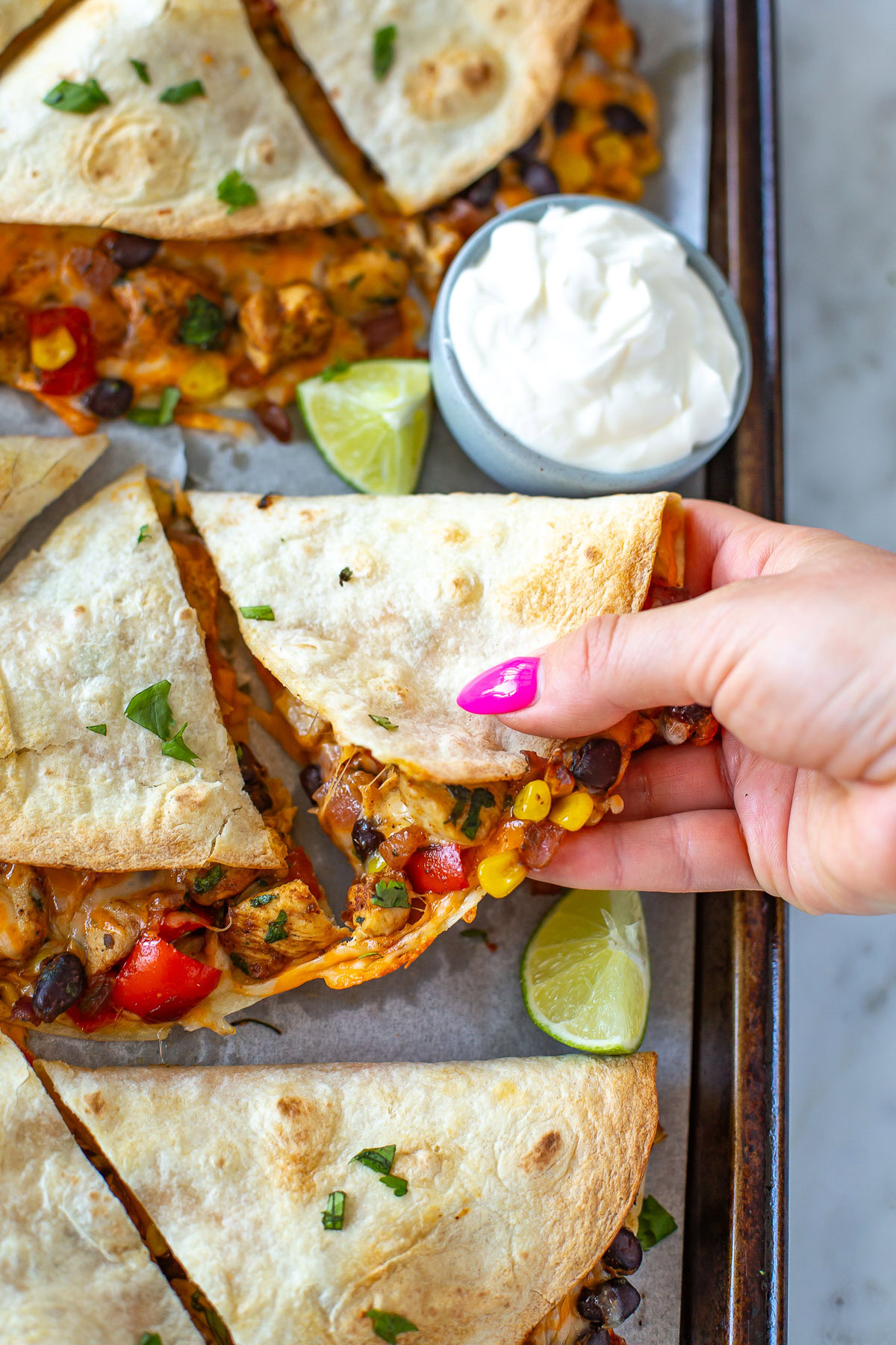 Overhead shot of a hand picking up a slice of a sheet pan quesadilla.