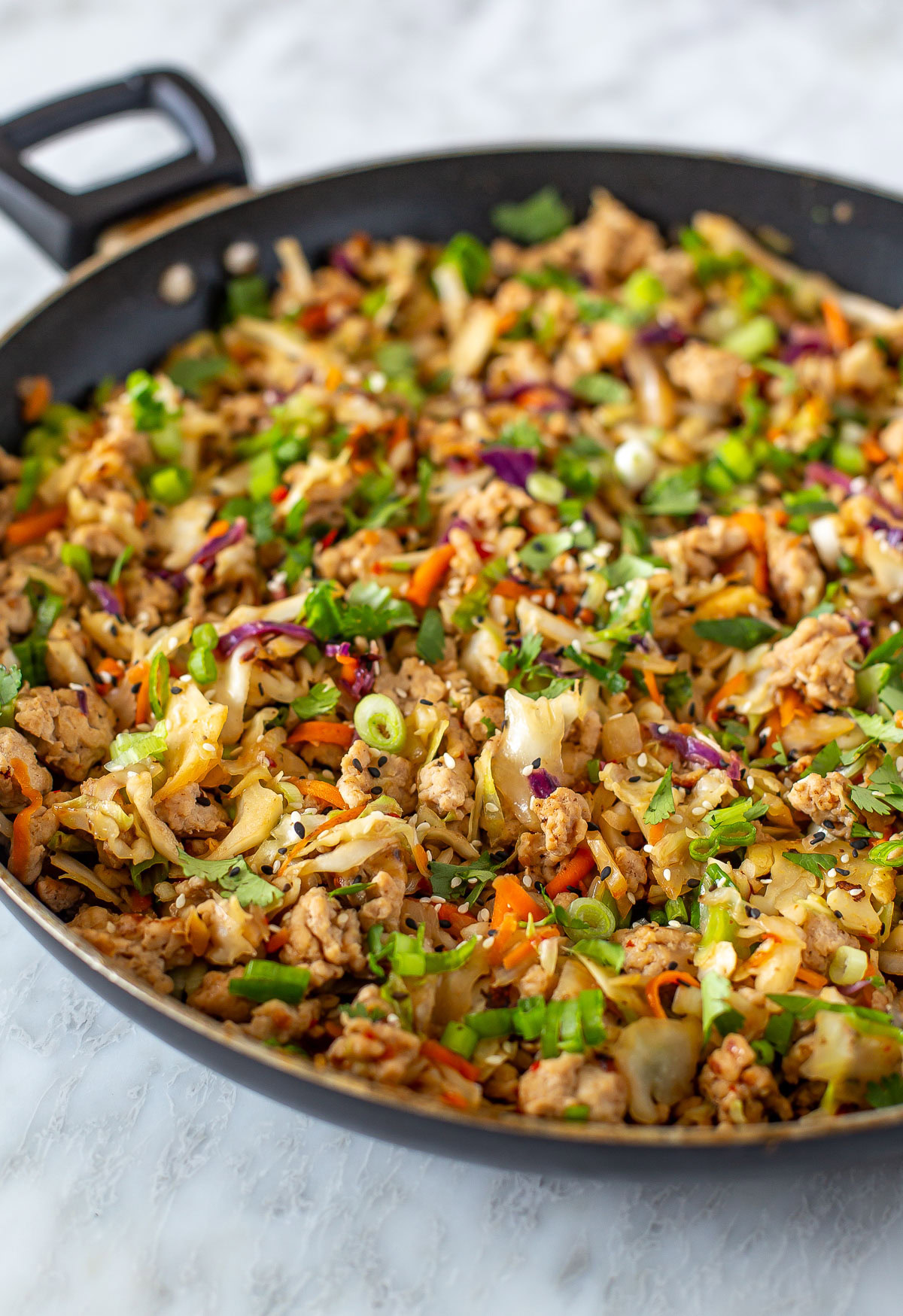 Side shot of a skillet filled with egg roll in a bowl.