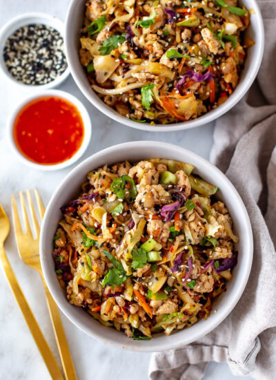 Overhead shot of two bowls of egg roll in a bowl with sauces and garnishes.