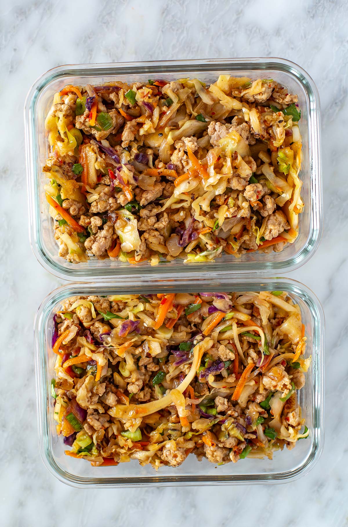 Overhead shot of two clear containers filled with egg roll in a bowl.