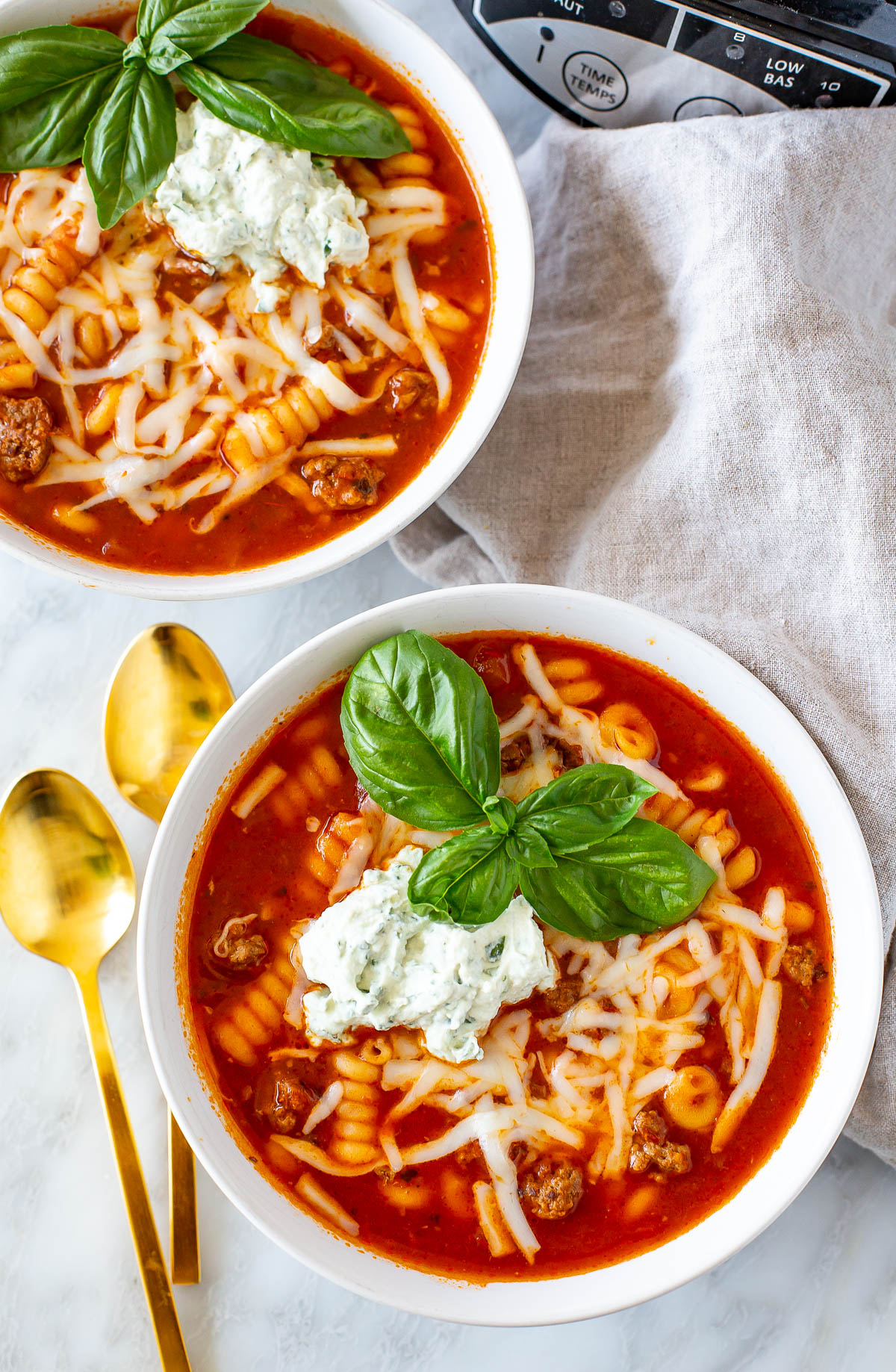 Overhead shot of two bowls of Easy Crockpot Lasagna Soup with gold spoons.