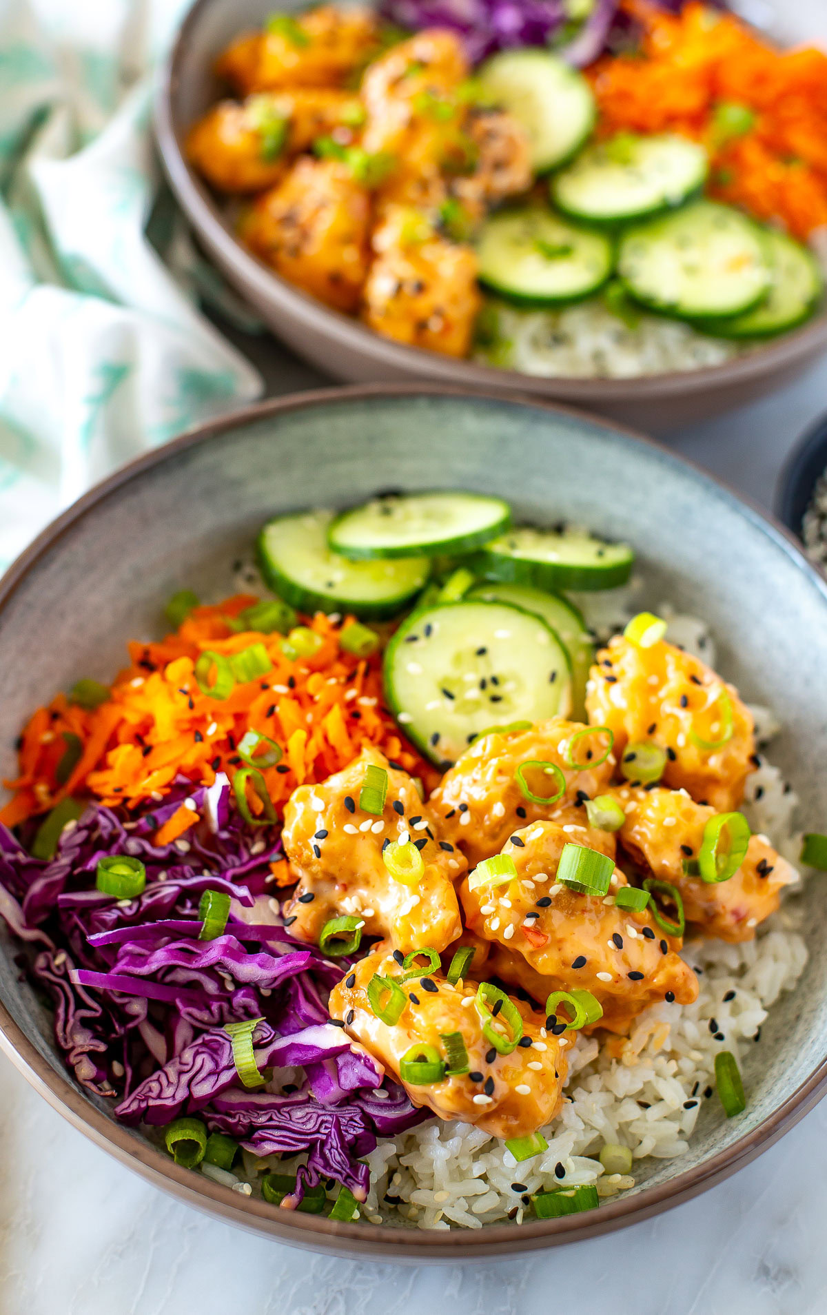 Side shot of two bowls of Bang Bang Chicken.