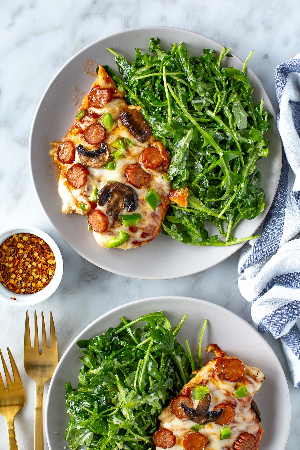 Plated overhead shot of pizza chicken with arugula side salad