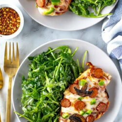 Plated overhead shot of pizza chicken with arugula side salad