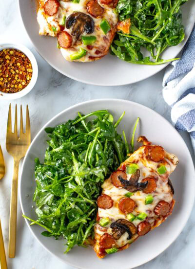 Plated overhead shot of pizza chicken with arugula side salad
