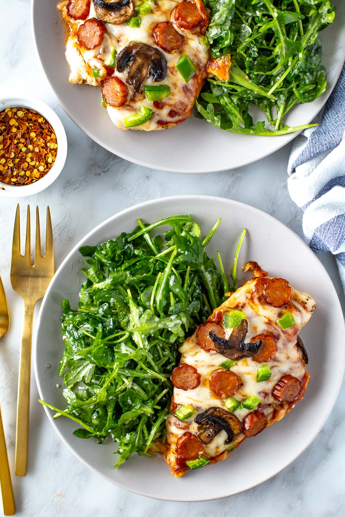 Plated overhead shot of pizza chicken with arugula side salad