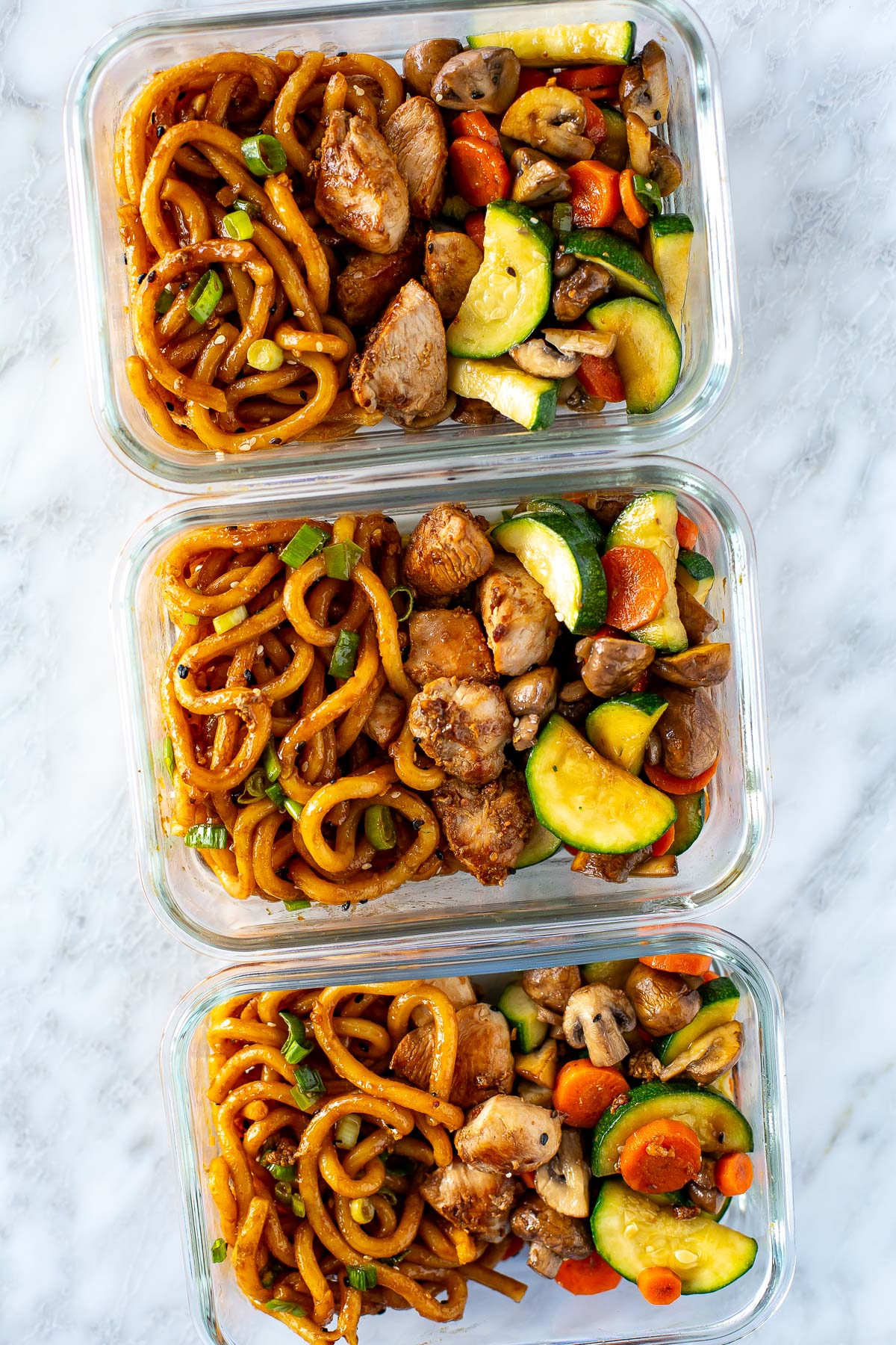Overhead shot of hibachi noodles with chicken and vegetables in meal prep containers
