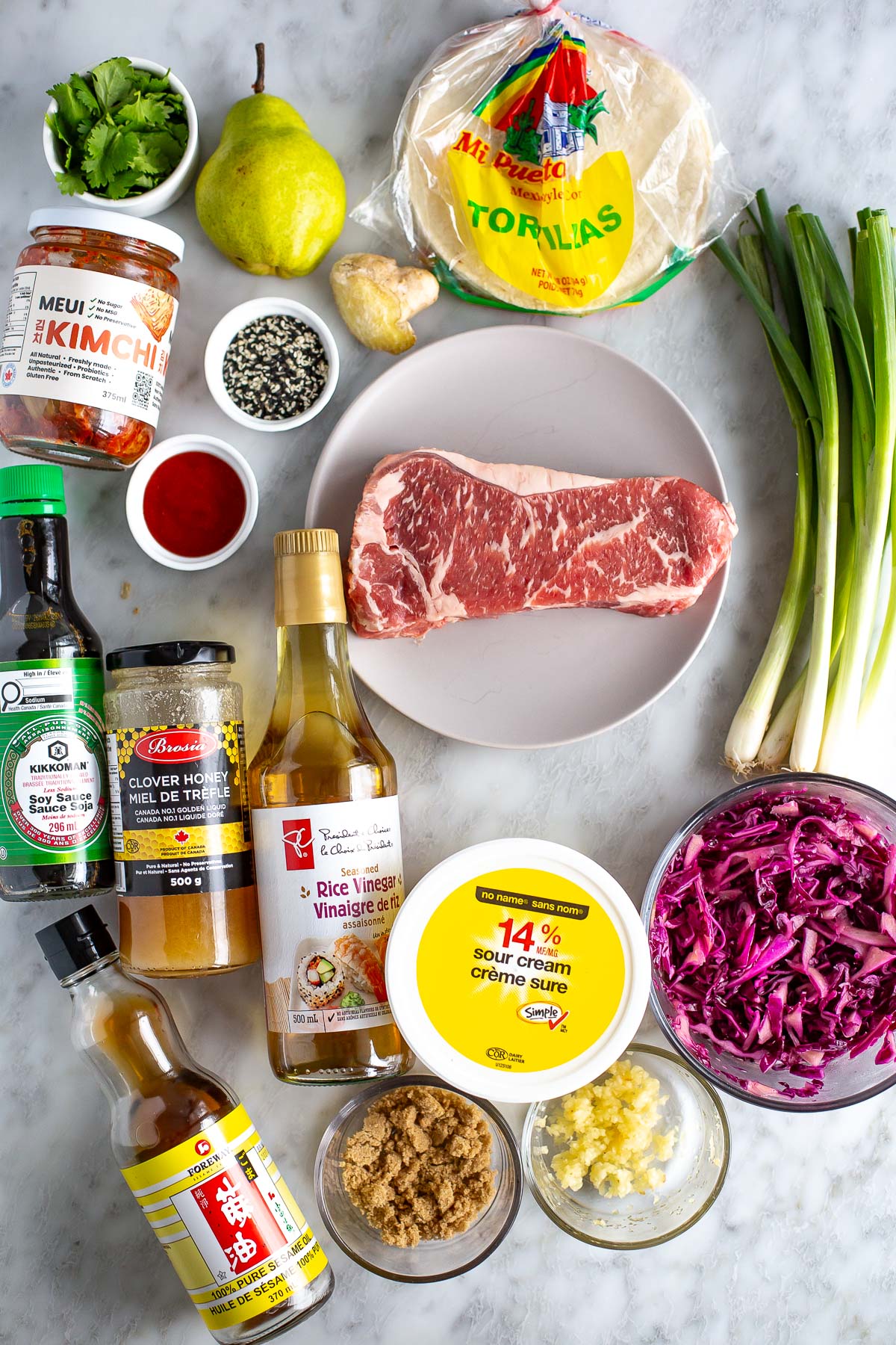 Fresh ingredients for Asian-inspired beef stir-fry on a marble surface.