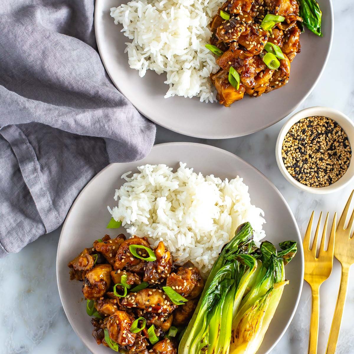 Two plates of ginger chicken served with bok choy and rice.