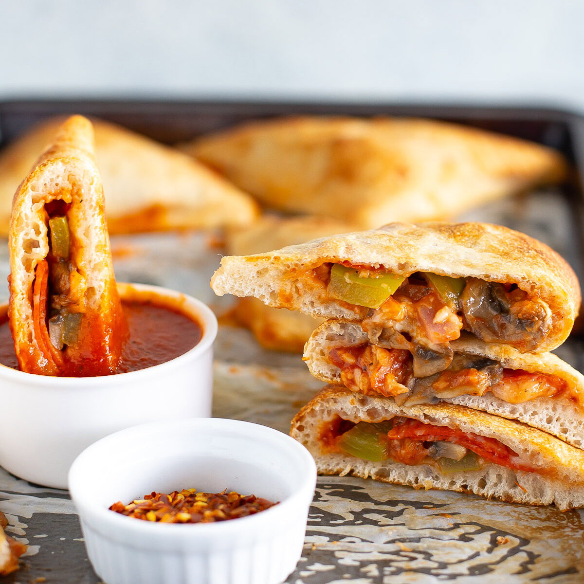 Homemade pizza pockets with a side of red chili flakes and extra marinara