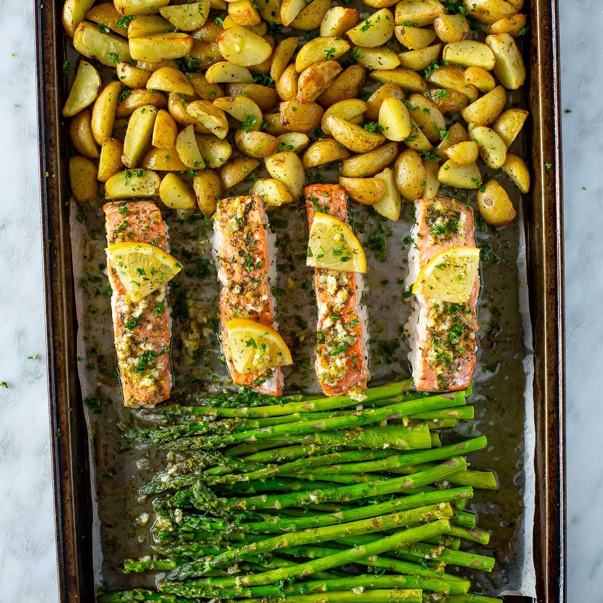 A sheet pan with roasted salmon, potatoes and asparagus.