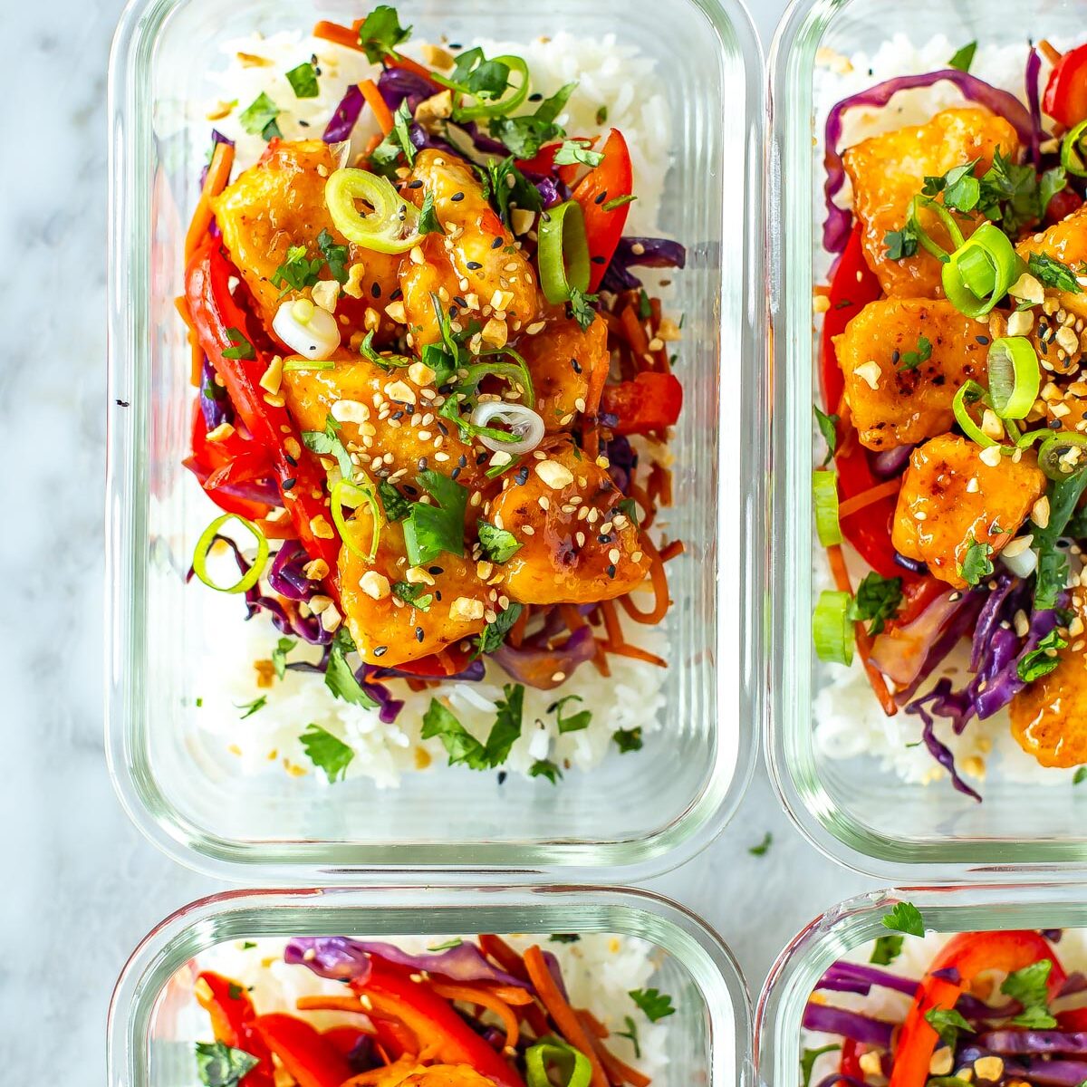 Four meal prep containers with sweet chili chicken inside.